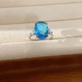 Detail of an oval-cut blue zircon ring in a silver-toned setting and jewelry box - Ring / Silver-Blue