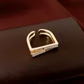 Gros plan d'une bague ouverte dorée géométrique avec incrustations blanches et zircons - Style Ouverture Carrée / Or