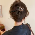 Close-up view of a leopard print flower hair clip styled on a brown hair bun updo - Leopard Flower Twist Clip / Black Leopard