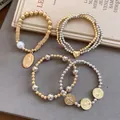 Detail view of 4pcs elastic beaded bracelets with heart and religious coin charms. - Four-Piece Set / Gold-Silver
