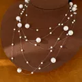Détail élégant d'un collier de perles blanches multicouche avec des fils transparents - Blanc
