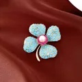 Detaillierte Nahaufnahme einer eleganten Blumenbrosche mit Türkissteinen und Perlenmitte - Französische Vintage Kleeblatt Blumen Brosche / Gold-Blau-Weiß