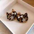 Close-up van luipaardprint kattenkop oorbellen met sprankelende strik en bloem in doosje. - Zilver-Koffie