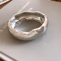 Detailed view of silver-finish wavy textured metal oval bangle on a neutral prop - Wave Texture Smooth Bracelet