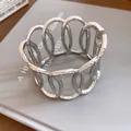 Detailed macro shot showing the textured silver metallic oval hollow open cuff bracelet - Multi-Layer Hollow Oval Stackable Bracelet
