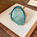 Detailansicht eines goldfarbenen Manschettenarmbands mit großem blauem Kunstharzstein. - Unregelmäßiges Dreieck (Blau) / Gold