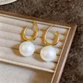 Detailansicht eleganter goldener Creolen mit großen runden weißen Perlenanhängern. - Weiße Perle Stil / Silberstift-Gold-Weiß