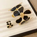 Gedetailleerd overzicht van elegante zwarte emaille bloem armband en ring set in goud - Ring Armband Set / Zwart