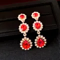 Detailweergave van rode edelsteen oorbellen met sprankelende kristallen in goudzetting - Zilveren oorknopje-Goud-Rood