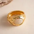 Dettaglio di un bracciale rigido in metallo dorato plissettato con intarsio in resina crema. - Oro-Bianco