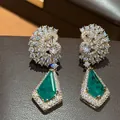 Vue rapprochée de boucles d'oreilles dorées 18 carats avec pierres vertes et zircons. - Aiguille en argent / Or-Vert