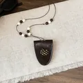Detailopname van bruine lederen buidelketting met gestippelde kattenhanger en kralen - Halsketting-Koffie-Kat