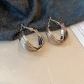Gros plan détaillé de boucles d'oreilles créoles argentées torsadées en C sur fond de tissu texturé - 2# Créole (Tige Argent)