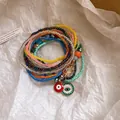 Nahaufnahme bunter böhmischer Perlenarmbänder mit Evil-Eye-Anhängern - 9-teiliges Set / Blau-Gelb-Orange-Rosa