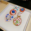 Detailweergave van unieke asymmetrische emaille oorbellen met bloem- en maanmotieven - Asymmetrisch Emaille Bloemenontwerp / Zilveren Stift Goud Blauw Rood
