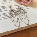 Elegante silberne Quastenohrringe mit ovalen Zirkoniasteinen auf einem Buchhintergrund - Langer Quastenstil (HE35777) / Silber