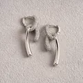 Détail macro de boucles d'oreilles nouées plaquées or 18 carats avec pavé de zircons - Argent