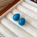 Makro-Nahaufnahme minimalistischer blauer Emaille-Ohrstecker in Tropfenform im Schmuckkästchen - Himmelblau