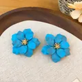 Close-up van schattige blauwe bloem oorknopjes met matte afwerking en goud - Blauw