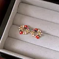 Detailaufnahme von Vintage-Marienkäfer-Ohrringen mit rosa Blumen und Kristalldetails. - Marienkäfer Geometrischer Kranz Stil (26#) / Gold/Rot Rosa