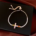 Vue détaillée de la croix en zircon coloré sur un élégant bracelet ajustable plaqué or. - Croix / Or/Multicolore