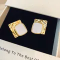 Dettaglio macro degli orecchini dorati con trama increspata e intarsio bianco - Oro-Bianco