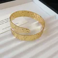 Gedetailleerde macro-opname van goud gehamerde textuur op de brede armband - Goud