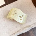 Nahaufnahme eines cremefarbenen Acrylarmreifs mit elegantem hohlem Blumenmuster-Design. - Acryl Hohl Blume Offener Armreif (HB6681) / Gelb
