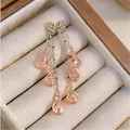 Macro detail of layered golden tassel earrings featuring faceted peach crystal pendants - Pink