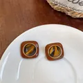 Close-up of vintage style square stud earrings featuring a tiger eye stone pattern inlay - Tiger Eye Square-Round Style / Gold Brown