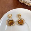 Detailed view of vintage gold-tone pleated earrings with brown cat-eye beads and crystals - Rhinestone Pleated Hoop Style / Gold Brown