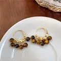 Detailed close-up view of vintage gold hoop earrings with dangling tiger eye beads - Tiger Eye Hoop Style / Gold Brown