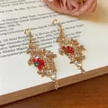 Gedetailleerd zicht op elegante gouden bloemenoorbellen met veel gekleurde strassteentjes - Oorhaken-Goud-Rood