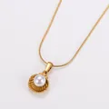 Detailed close-up of a gold shell pendant with a white pearl on a delicate chain - Gold White