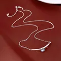 Dettaglio di una collana argentata con pendente curvo e una pietra azzurra luminosa. - Argento-Blu