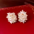 Nahaufnahme von eleganten facettierten Kristall-Cluster-Ohrsteckern mit Goldakzenten - Weiß