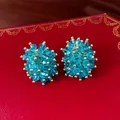 Elegante hellblaue Kristall-Cluster-Ohrringe mit Goldakzenten auf einer roten Geschenkbox - Blau