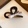 Detail van roze acryl haarklem met strik en gouden handgemaakt metalen embleem - Roze Strik Stijl (HH10008) / koffiekleur