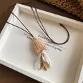 Detailed view of a vintage wooden fish pendant featuring shell bead tassels on a dark cord - Necklace-Brown-White