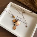 Detail showing handmade ethnic pendant necklace with wooden fish and shell charms - Necklace-Brown-White-Cat