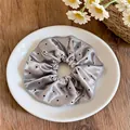 Détail d'un chouchou en satin gris à pois présenté sur une assiette blanche. - Chouchou en Satin à Pois / Gris à Pois