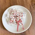 Détail d'un chouchou à imprimé fraise avec bordures en dentelle et un nœud rouge - Chouchou Nœud Imprimé Fraise / Style Floral Rouge et Blanc