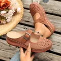 Detail of brown platform clogs featuring hollow-out floral patterns and buckle strap. - 36 / Brown