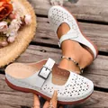 Detailed view of white hollowed-out wedge mules featuring an adjustable buckle strap. - White