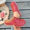 Detalle de mules de cuero rojo vintage con motivos calados y un lazo decorativo. - Rojo