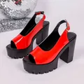 Detailed close-up view of red patent leather platform sandals with chunky high heels. - 35 / Red