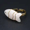 Close-up of handmade wire-wrapped fish-shaped natural stone ring with gold band - Fish Shaped Carving (aljylr2064) / Rose Quartz
