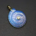 Detailed macro view of a carved opalite nautilus shell pendant featuring a zircon center. - Opal