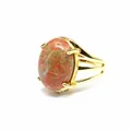 Primo piano di un anello placcato oro con una grande pietra ovale di diaspro rosso e verde. - Unakite