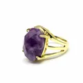 Close-up detail view of a retro golden open ring featuring a large oval faceted purple stone - Amethyst